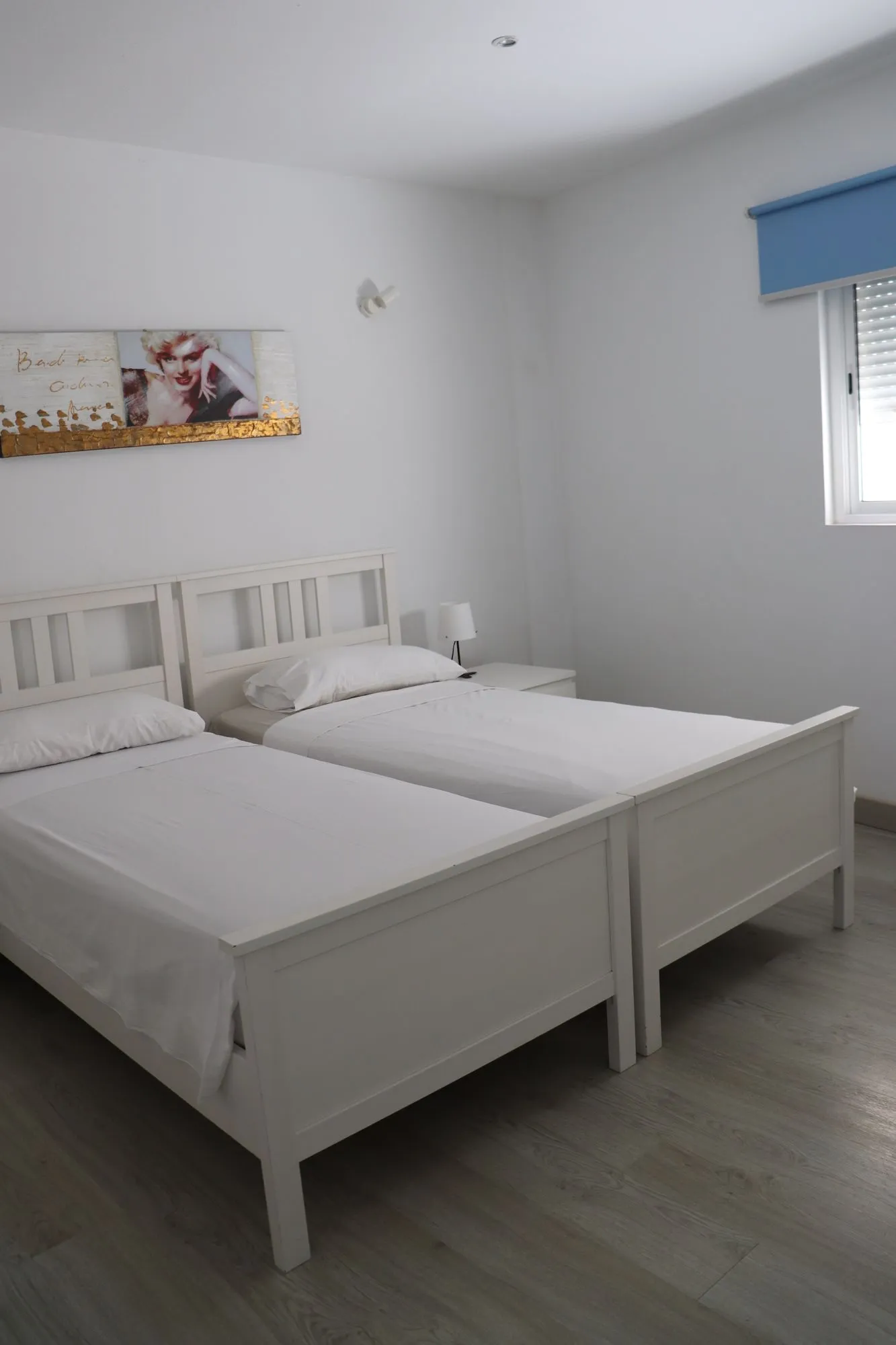 Camera da letto di Casa Gabriel con due letti singoli bianchi e finestra con tenda blu