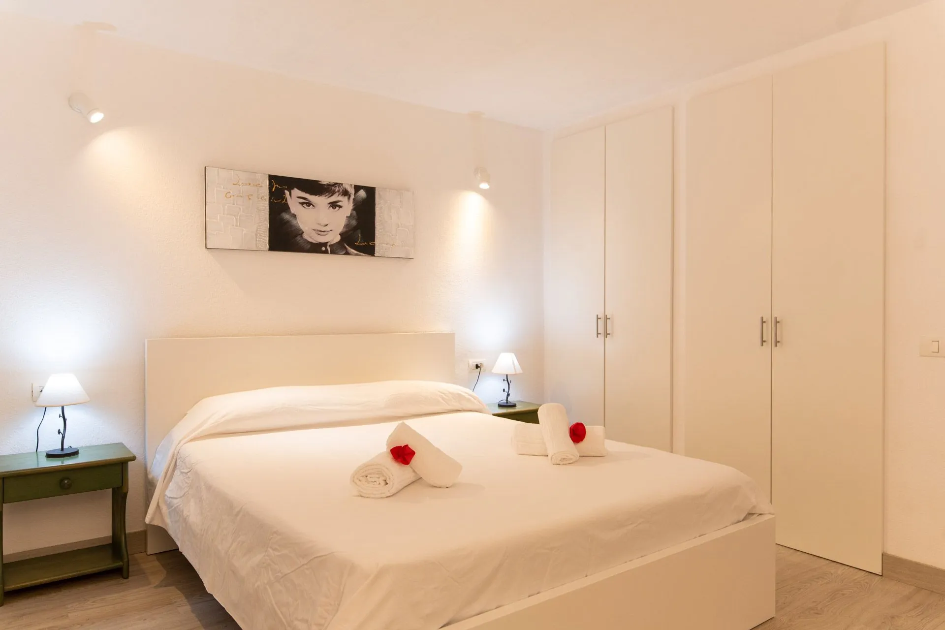 Camera da letto di Casa Wonder con quadro sopra il letto e armadi bianchi a muro