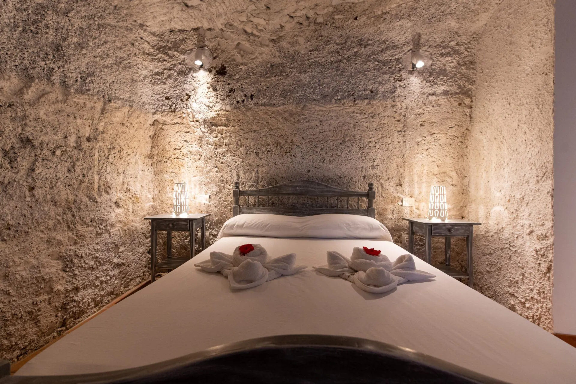 Letto matrimoniale con asciugamani a fiore in camera scavata nella roccia, Casa Sting