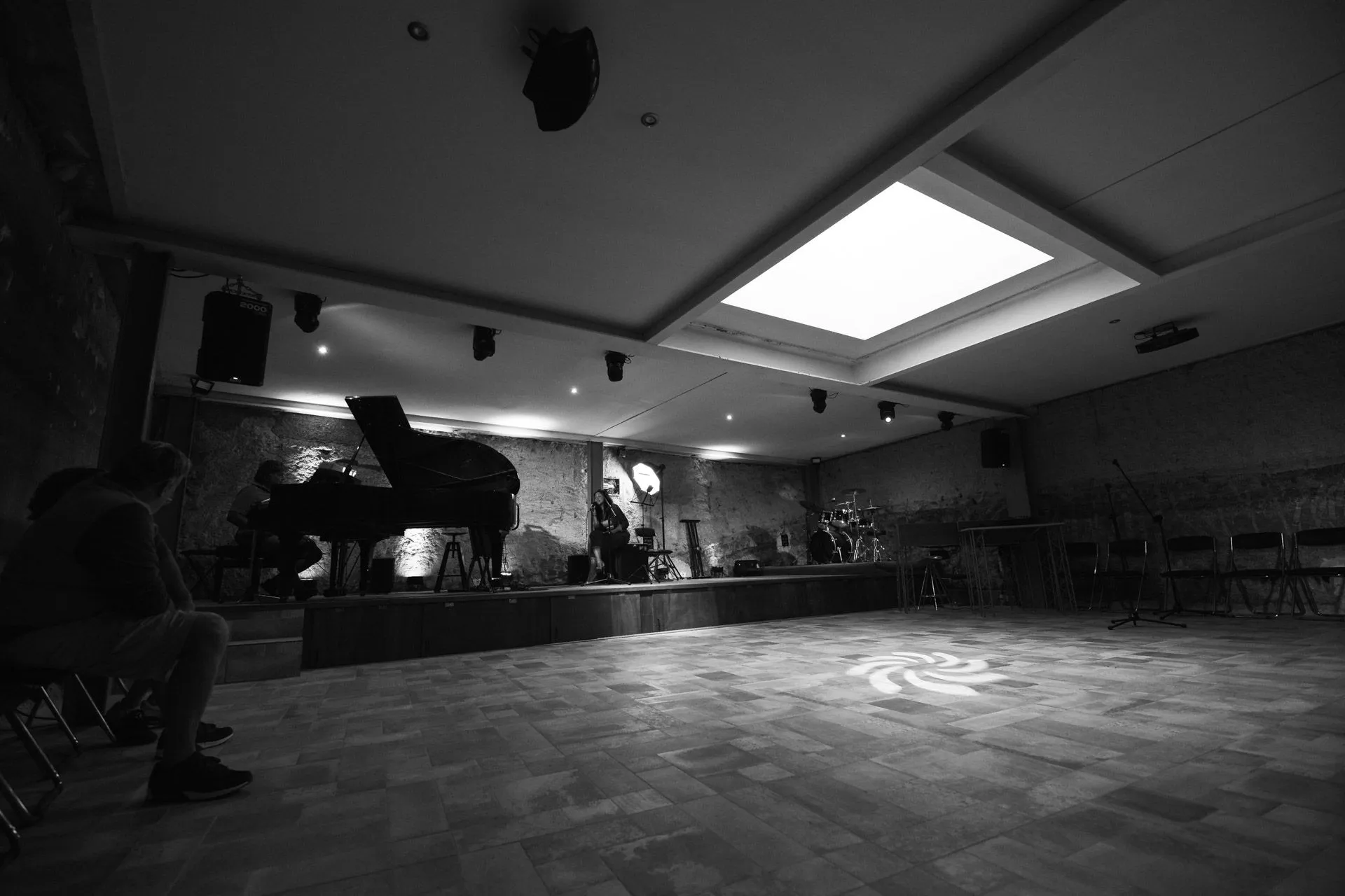 Persone sedute ad assistere a un concerto al pianoforte nella sala buia