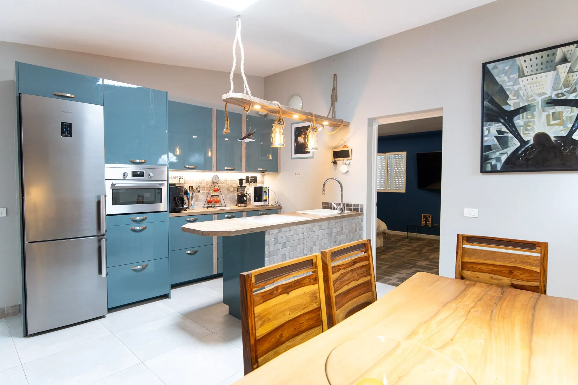 Cucina con mobili blu, elettrodomestici in acciaio e tavolo in legno con sedie
