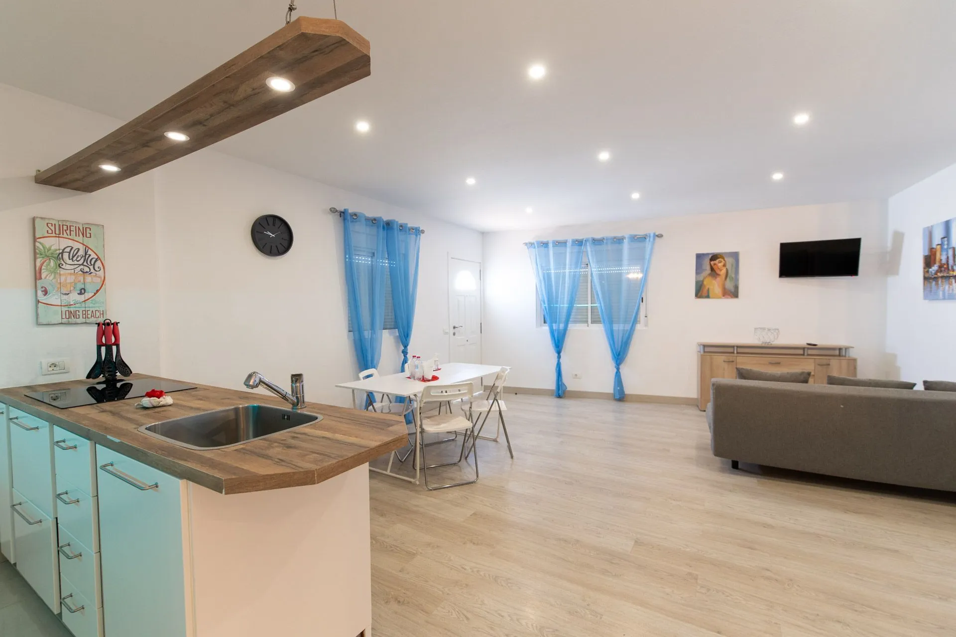 Cucina open space con isola centrale e zona pranzo con tende blu
