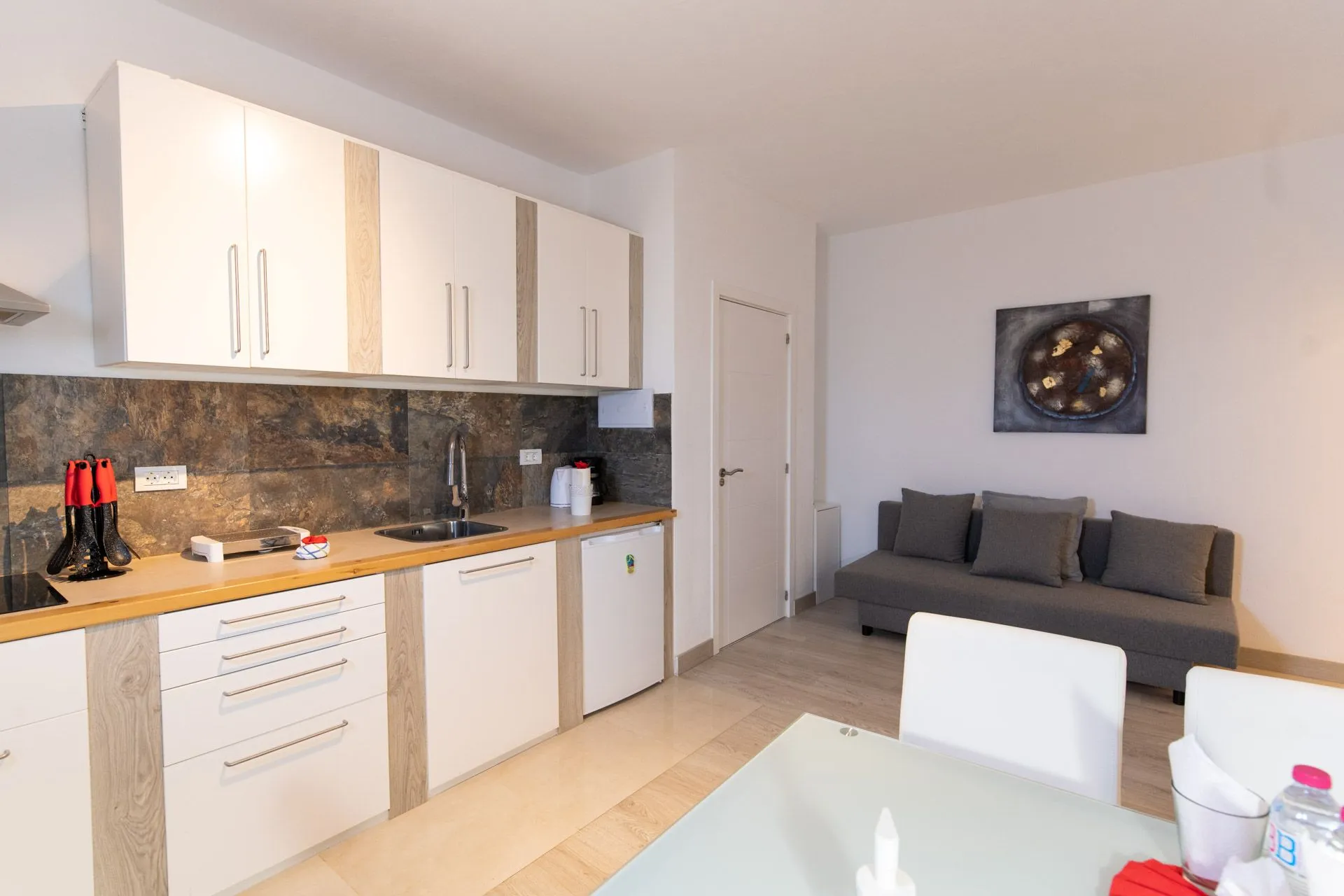 Cucina open space con divano grigio e quadro a parete
