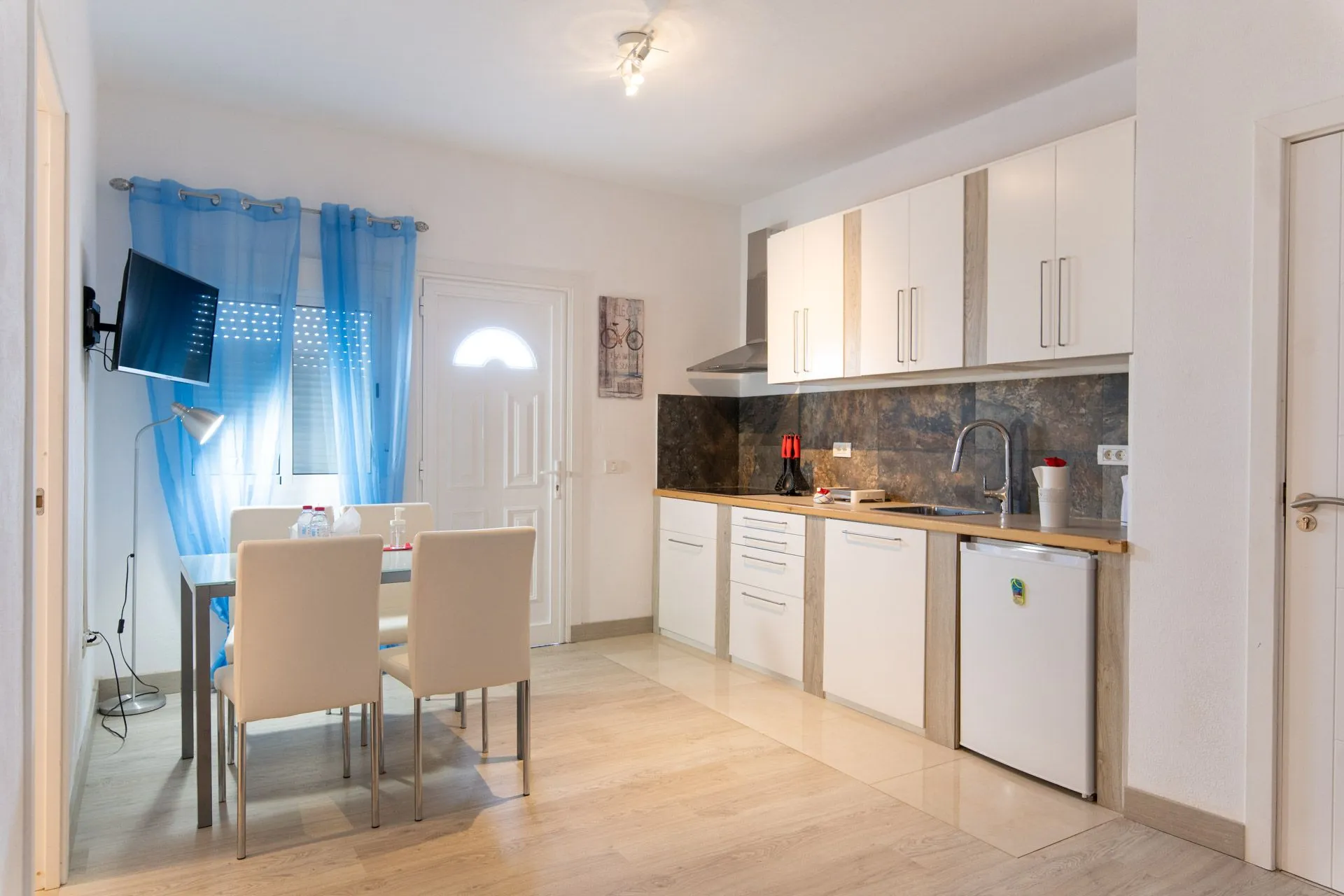 Cucina e zona pranzo con tende azzurre e sedie beige