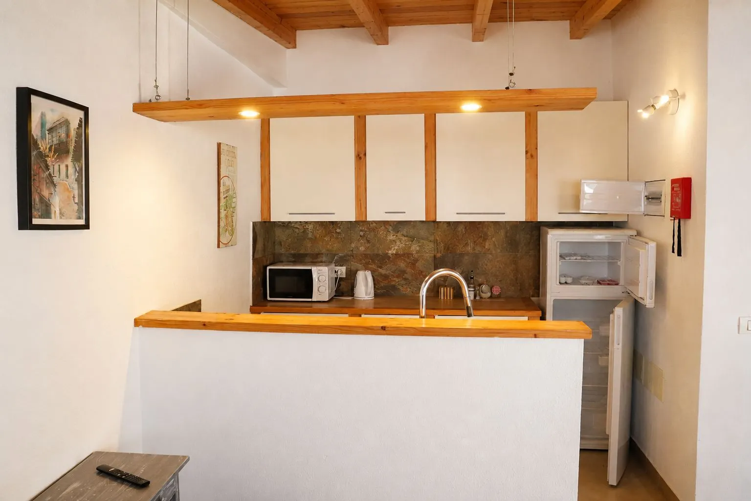 Cucina in legno con travi a vista, mobili bianchi e frigorifero aperto a Casa Wonder