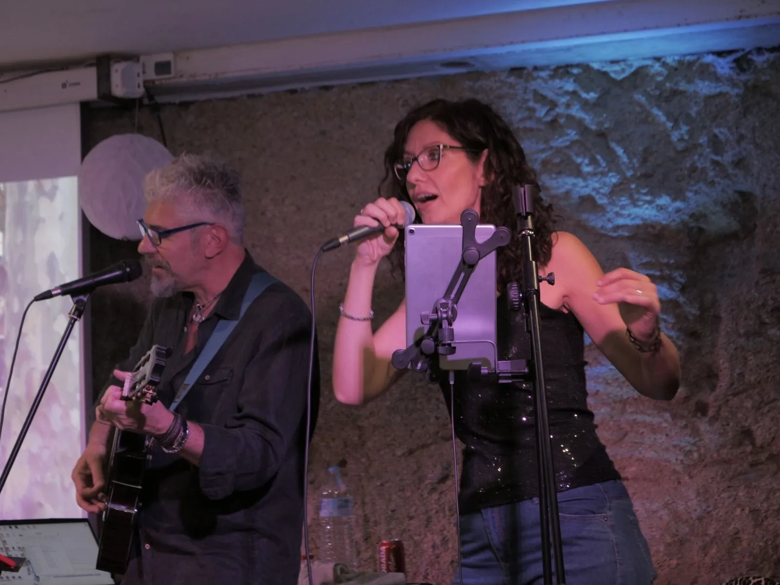 Duo musicale si esibisce con chitarra e microfono durante un concerto