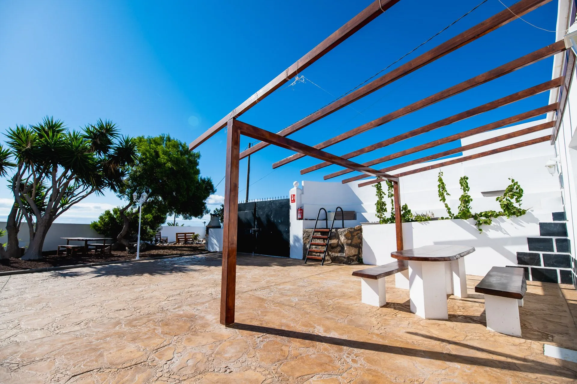 Pergola in legno con tavoli in pietra in un cortile esterno soleggiato