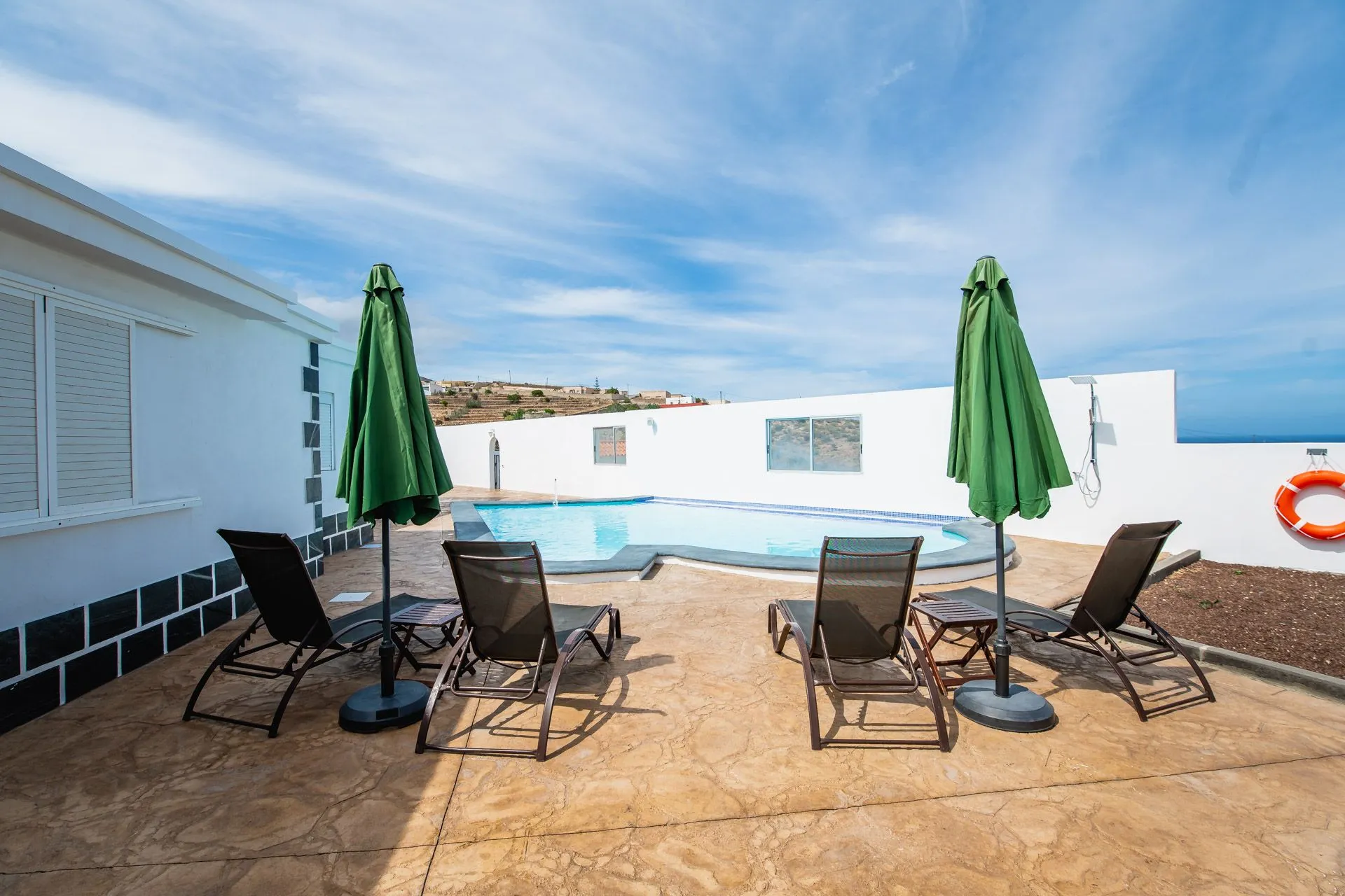 Piscina con lettini e ombrelloni verdi, vista sulla collina e il mare