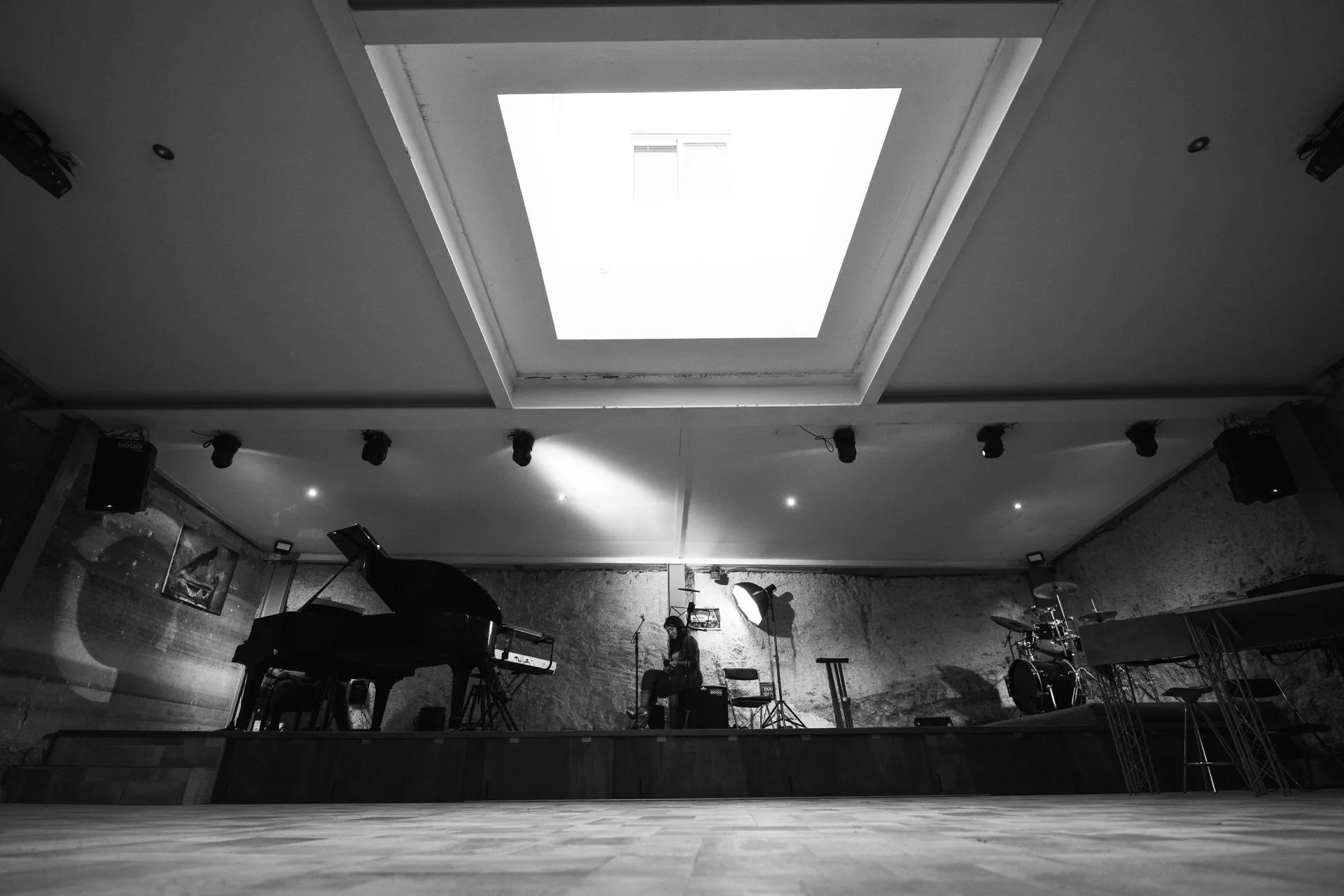 Sala concerti vista dal basso con pianoforte a coda, batteria e lucernario centrale