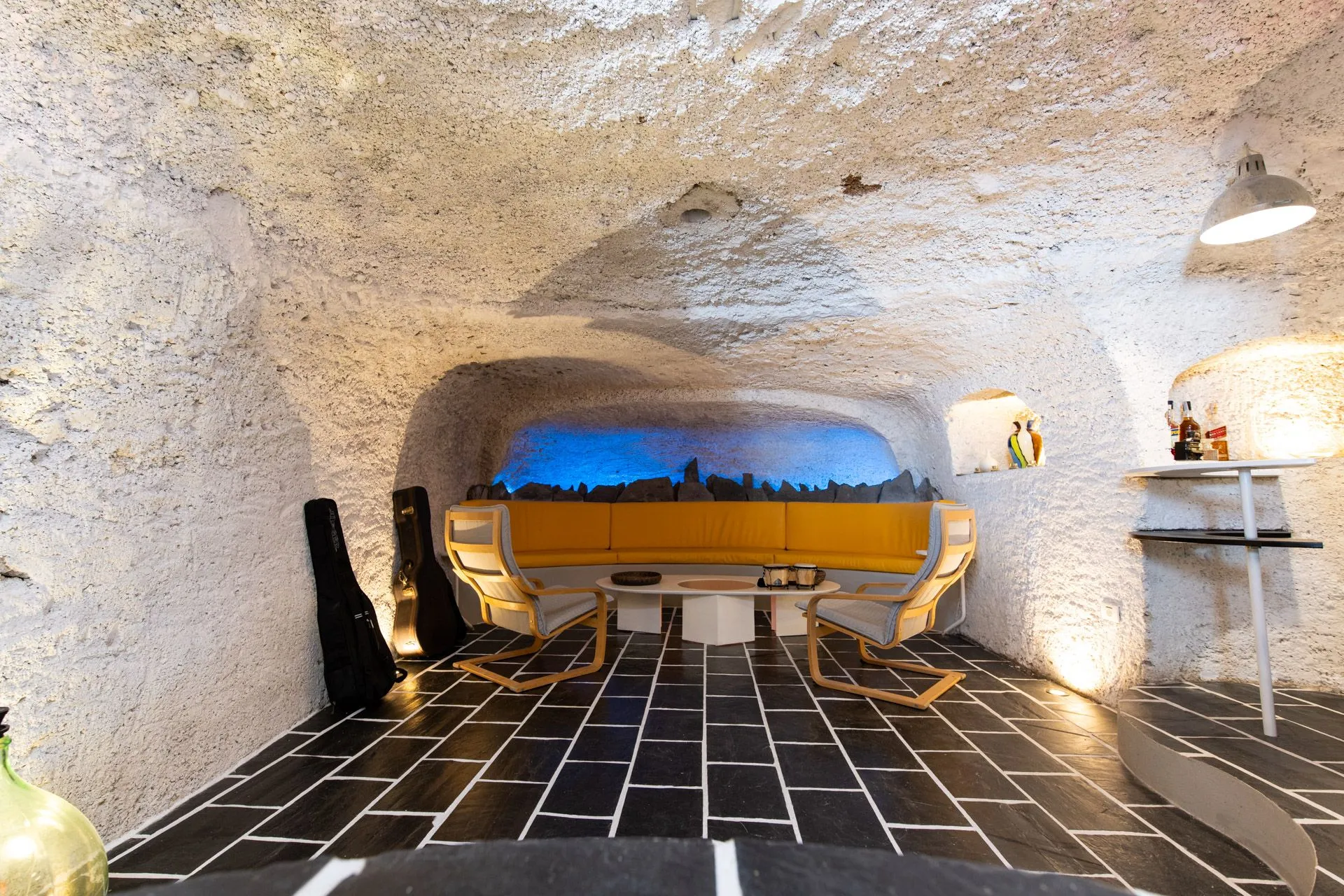Salotto scavato nella roccia con divano giallo e illuminazione blu nella Suite Mozart