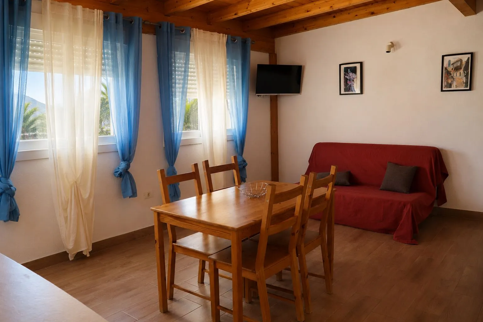 Soggiorno con divano rosso, tende blu e bianche e tavolo in legno a Casa Wonder