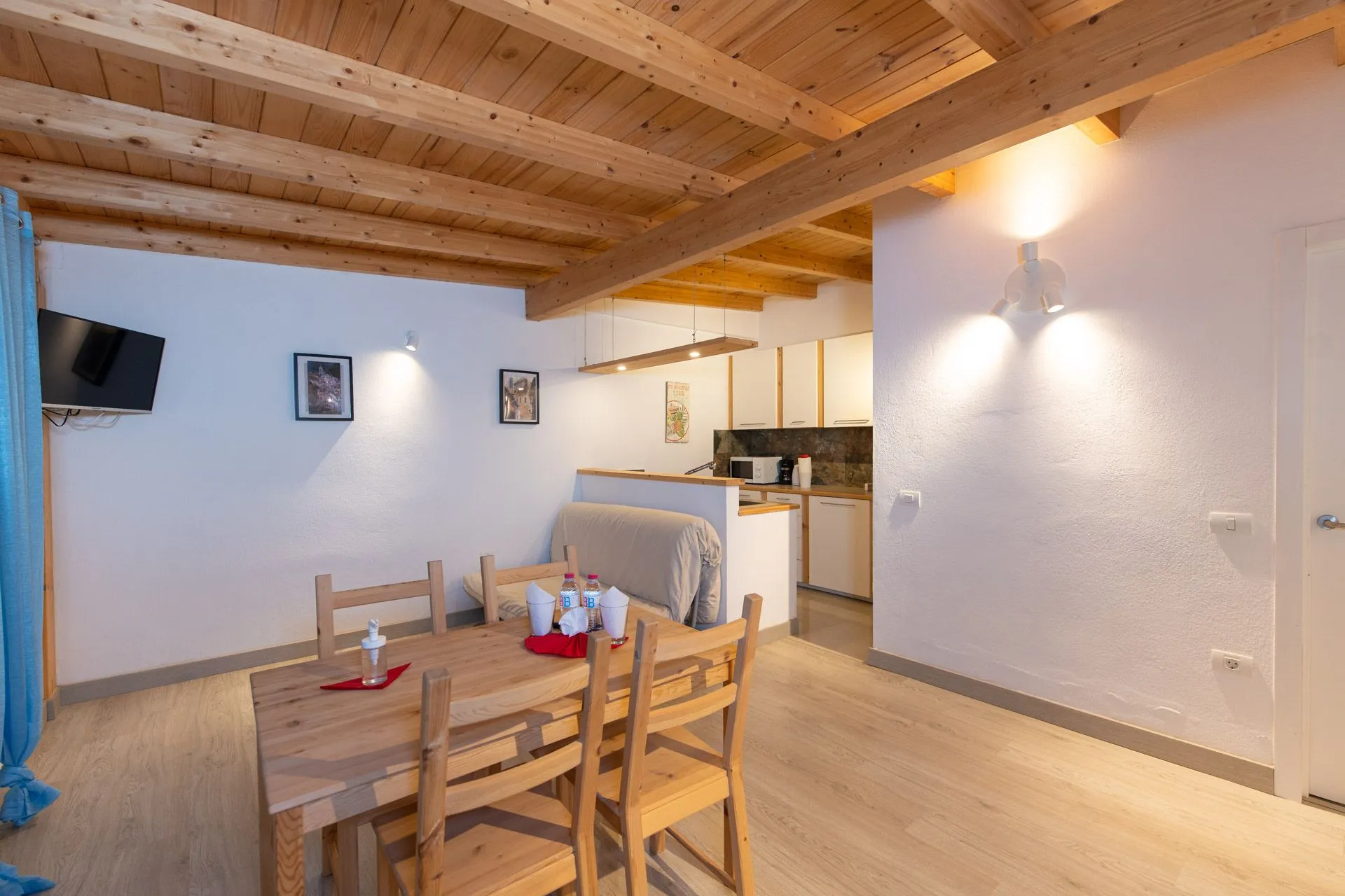 Soggiorno con soffitto in legno, tavolo da pranzo e cucina sullo sfondo a Casa Wonder