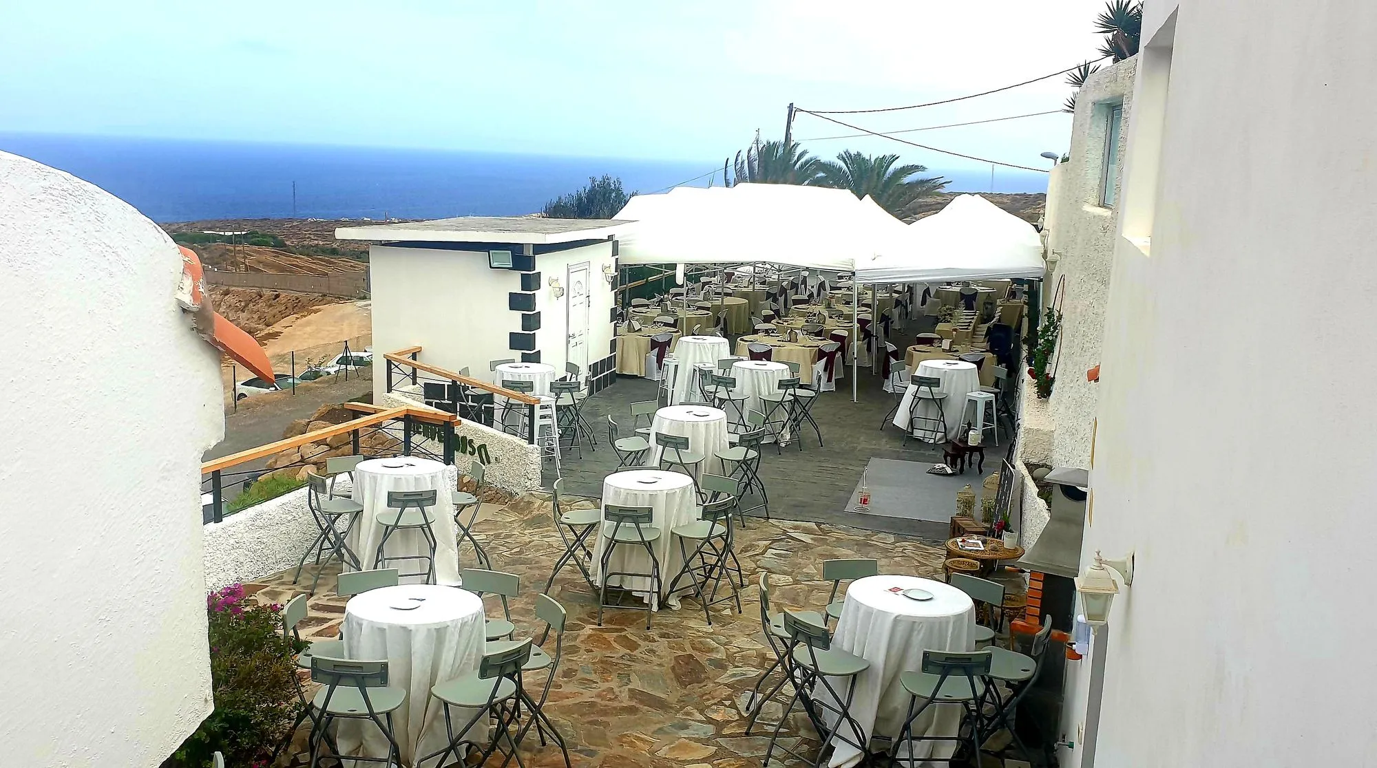 Terrazza con tavoli rotondi allestiti e gazebo con vista sull'oceano alla MJ's Concert Hall